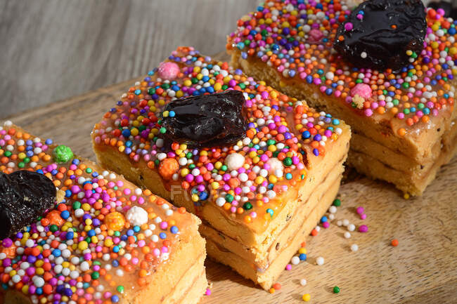 De haut de sucré Turron de Dona Pepa gâteaux au nougat décoré de dragées colorées et pruneaux servis sur table en bois — Photo de stock