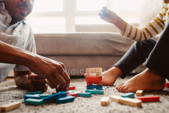 D'en haut, père et fils anonymes jouant avec des pièces de construction dans la salle à manger de la maison — Photo de stock