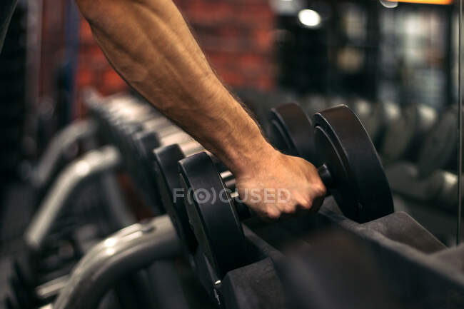 Рука сильного мужчины с гантелями в спортзале — стоковое фото