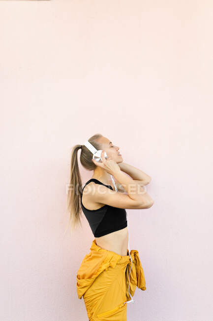 Jovem caucasiana vestindo fones de ouvido e roupas esportivas e ouvir música — Fotografia de Stock