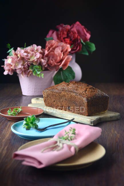 Natura morta di un pan di Spagna vicino ad alcuni vasi rosa con fiori su un tavolo — Foto stock