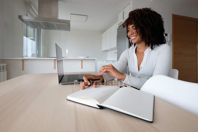 Fröhliche afroamerikanische Freelancerin spricht im Videochat, während sie von zu Hause aus arbeitet und Netbook nutzt — Stockfoto