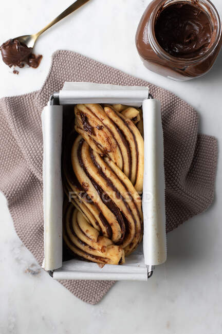 Bolo Babka não cozido com pasta de chocolate colocada no papel manteiga em prato de metal na cozinha — Fotografia de Stock