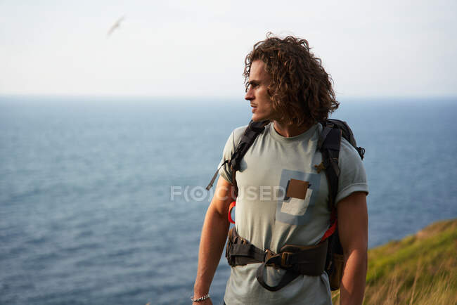 Чоловічий рюкзак, що ходить по пагорбу під час пішохідної подорожі влітку і дивиться вбік — стокове фото