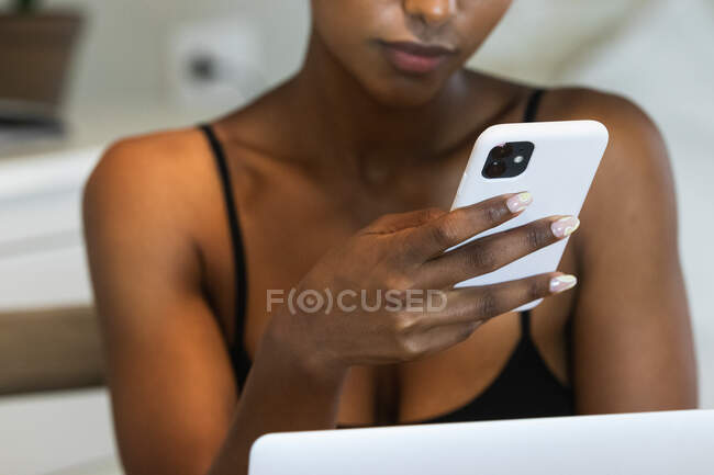 Crop irriconoscibile afro-americano navigazione Internet femminile sul telefono cellulare mentre seduto sulla sedia a casa — Foto stock