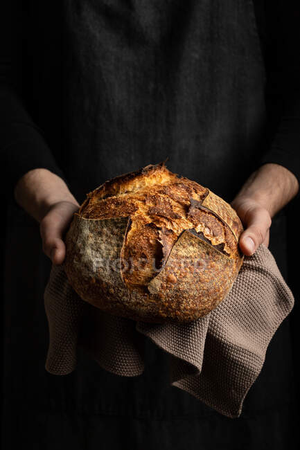 Unrecognizable crop chef in grembiule in piedi con pezzo di pane appena sfornato — Foto stock