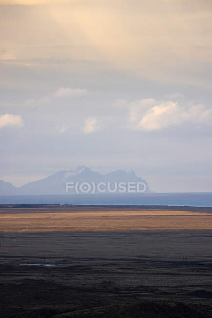 Nubes flotando en el cielo sobre el mar tranquilo y la costa llana en la mañana en Islandia - foto de stock