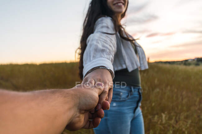 Пара тримається за руки в полі на заході сонця. — стокове фото