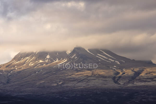 Nuvens grossas flutuando no céu da manhã sobre cume da montanha coberta de neve na Islândia — Fotografia de Stock