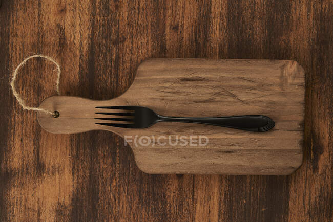 From above scratched chopping board with fork placed on rustic lumber table — Stock Photo
