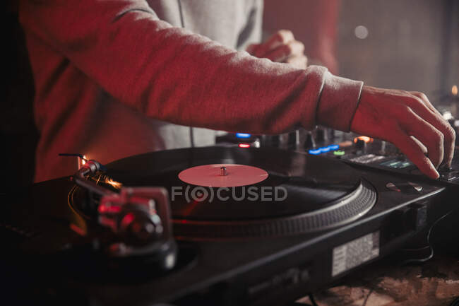 Vista lateral de la cosecha macho DJ mezcla de música en el controlador durante el concierto en la discoteca oscura - foto de stock