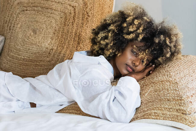 Attraente donna afroamericana sdraiata sdraiata sul letto a guardare la fotocamera — Foto stock