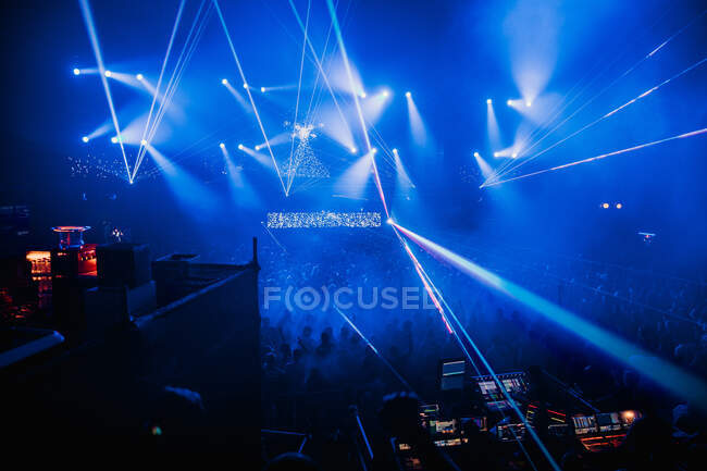 Luminosi raggi al neon blu illuminano la moderna sala da concerto scura durante la performance musicale dal vivo — Foto stock