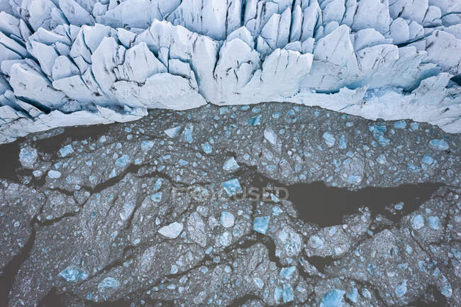 Desde arriba vista del dron de los témpanos de hielo flotando en el agua fría cerca de glaciar áspero en invierno en Islandia - foto de stock