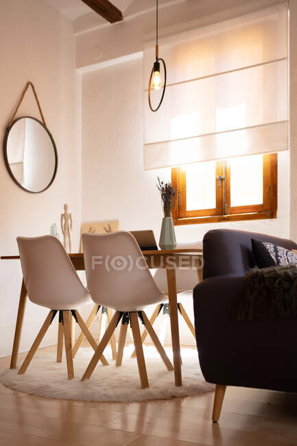 Современный интерьер столовой с деревянным столом и удобными стульями в уютной квартире — стоковое фото