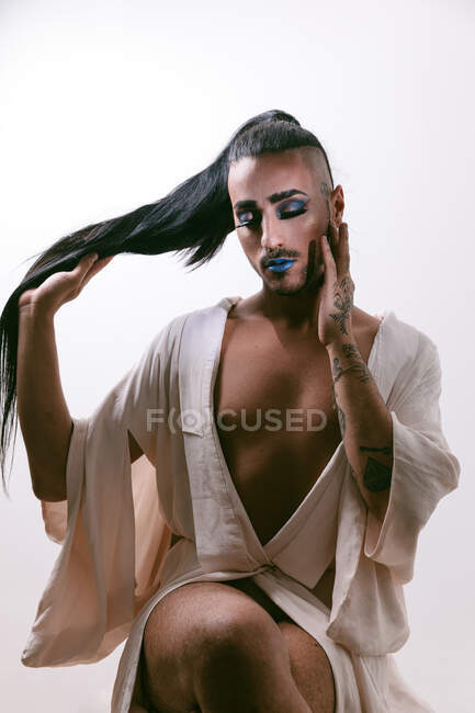 Portrait of glamorous transgender bearded woman in sophisticated make with closed eyes against neutral background — Stock Photo