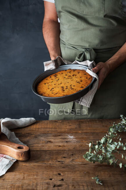 Cropped anonymous male cook holding plate with delicious pumpkin pie on lumber table — Stock Photo