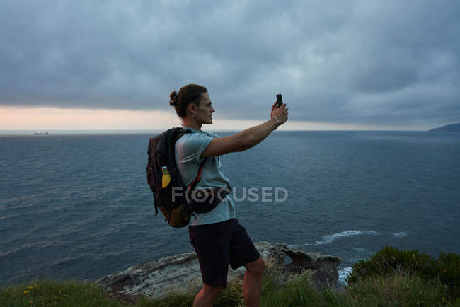 Side view male traveler taking picture of sky on smartphone in summer — Stock Photo