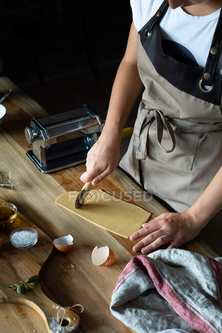 Persona irreconocible preparando raviolis y pasta en casa. Ella está cortando los platos de pasta - foto de stock