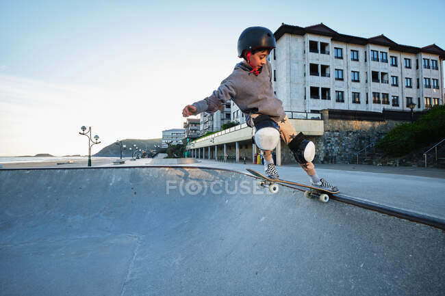 Зверху хлопчик показує трюк на скейтборді, тренуючись на пандусі і стрибаючи в скейт-парку — стокове фото