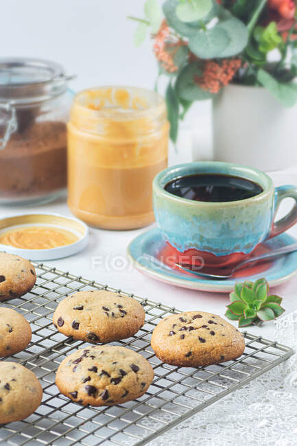 Bodegón de galletas fritas de chocolate recién hechas con mantequilla de maní y espolvoreos al lado de un café - foto de stock