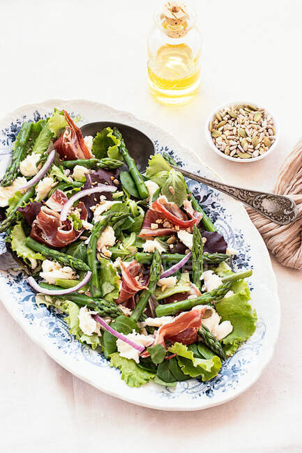 De cima delicioso prosciutto, mussarela e salada de espargos no fundo da mesa branca — Fotografia de Stock