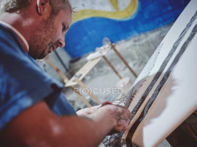 Kerl mit Tattoos und Ausrüstung steht neben weißem Surfbrett im Keller — Stockfoto