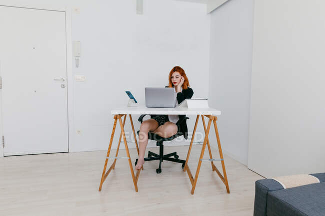 Молодая предпринимательница работает на нетбуке за столом с планшетом и смартфоном дома — стоковое фото
