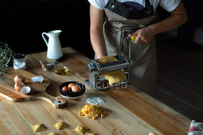 Pessoa irreconhecível preparando raviolis e massas em casa. Ela está usando uma máquina de massas — Fotografia de Stock