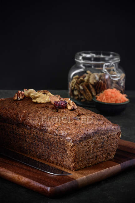 Vista laterale di una torta di carote accanto agli ingredienti su uno sfondo rustico — Foto stock
