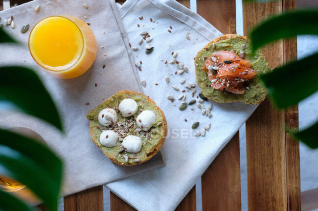 Gläser Saft und Kräutertee serviert auf Holztisch mit verschiedenen gesunden Avocado-Toasts mit Käse und Lachs während des Frühstücks im Outdoor-Café — Stockfoto