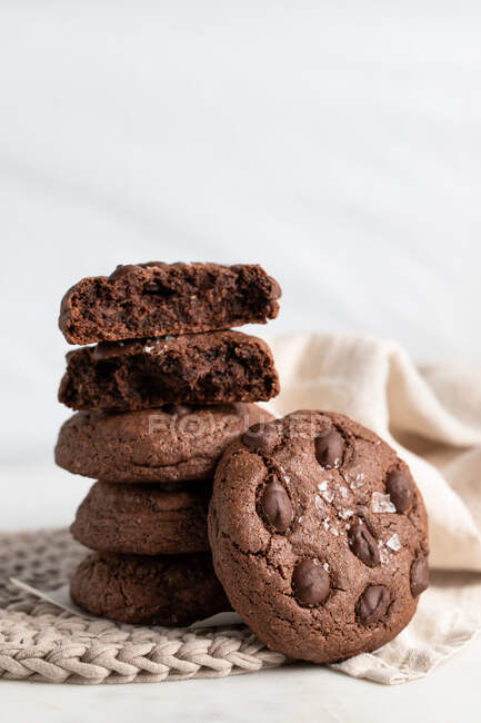 Pile of chocolate rye cookies placed on wicker plate near napkin on white background — Stock Photo