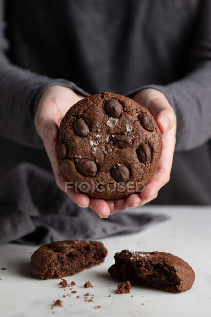 Cozinheiro irreconhecível em pé à mesa na cozinha com deliciosos biscoitos de centeio de chocolate — Fotografia de Stock