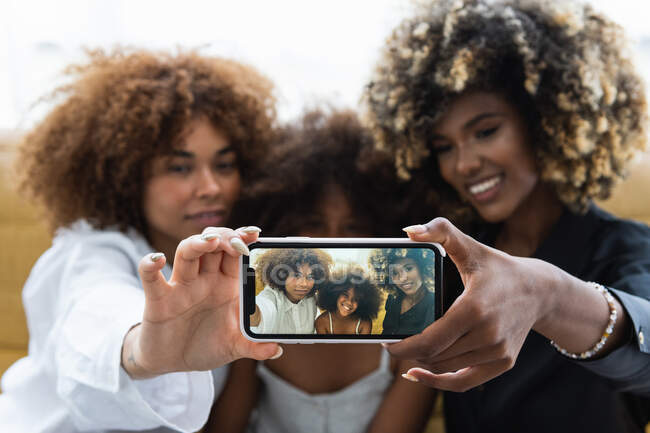 Soft focus de femmes afro-américaines prenant selfie via smartphone avec fille noire avec coiffure afro — Photo de stock