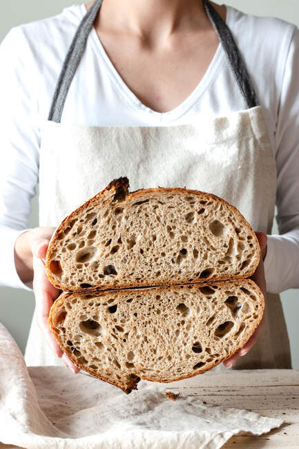 Crop faceless woman hands holding freshly baked sourdough rye bread Crumb white cutting in half — Stock Photo
