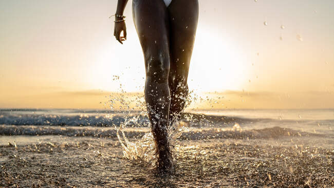 Mulher negra de colheita com tranças correndo na praia — Fotografia de Stock