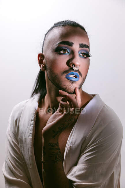 Retrato de mujer barbuda transgénero glamorosa en sofisticado hacen mirar hacia otro lado contra fondo neutro - foto de stock