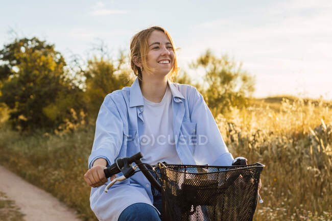 Блондинка, молода жінка, їде на велосипеді. захід сонця — стокове фото