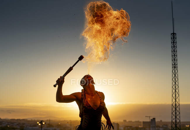 Feuerschluckerin spuckt Feuer bei Sonnenuntergang — Stockfoto