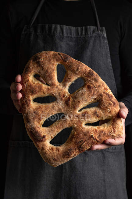 Crop chef masculin dans tablier debout avec pain fraîchement cuit de fougasse — Photo de stock