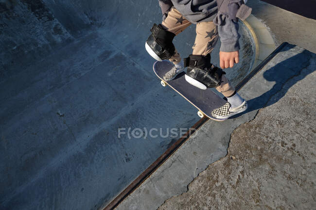 Dall'alto del raccolto anonimo pattinatore maschile in piedi con skateboard su rampa in skate park — Foto stock