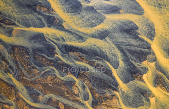 Сверху воздушный вид на реку с оранжевой водой, протекающей через грубую сельскую местность в Исландии — стоковое фото
