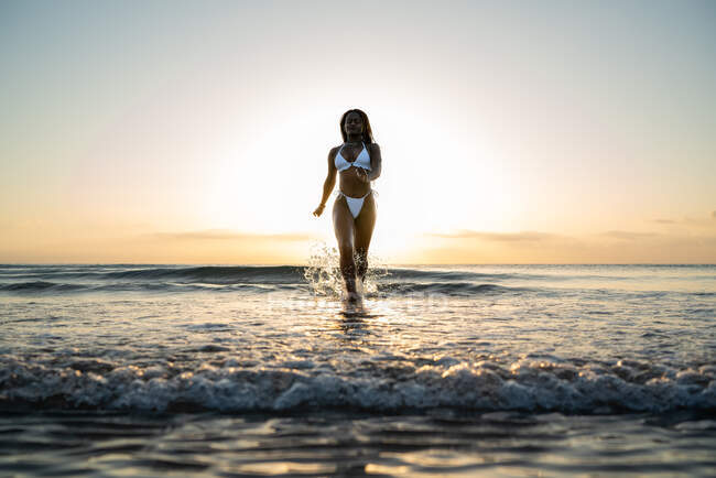 Mujer negra con trenzas corriendo por la playa - foto de stock