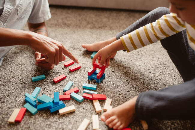 From above anonymous father and son playing with construction pieces in the dining room of the house — Stock Photo
