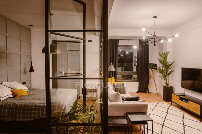 Interieur einer modernen Wohnung mit Schlafzimmer mit Wand trennendem Wohnzimmer mit Sofa und Fernseher — Stockfoto