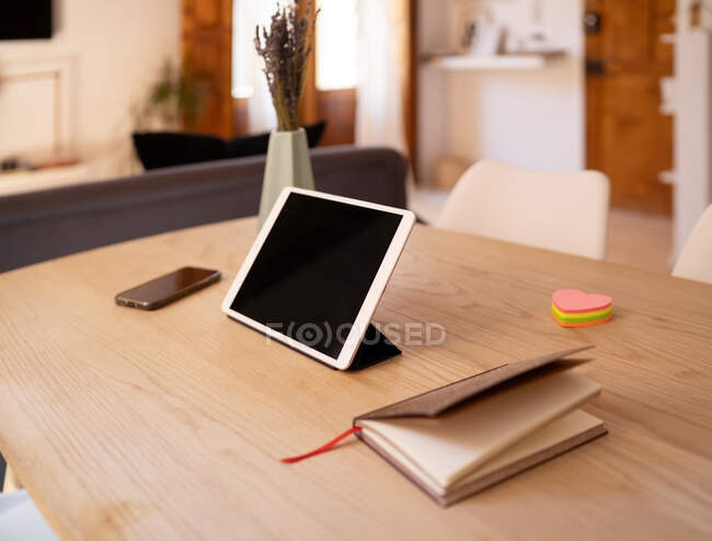Modern tablet with black screen placed on table with smartphone and notepad at home — Stock Photo