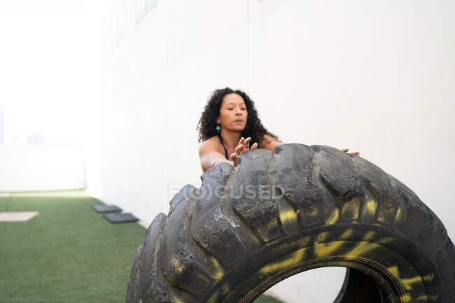 Muskulöse asiatische Athletin kippt bei intensivem Training schweren Reifen um — Stockfoto
