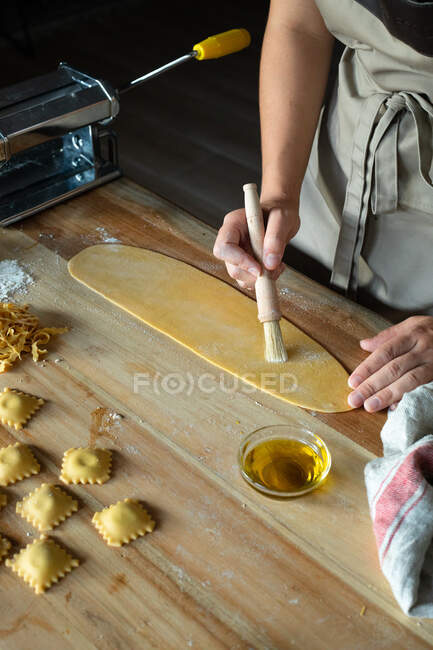 Неузнаваемый человек готовит дома равиоли и макароны. Она рисует макароны с яйцами. — стоковое фото