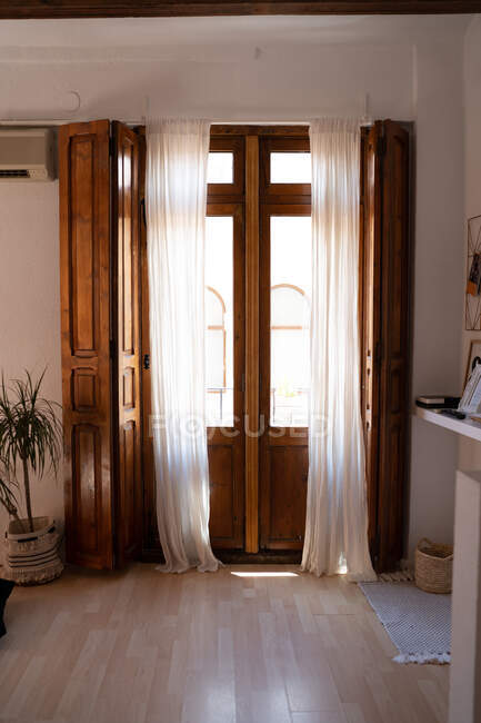 Acogedor interior de habitación con puertas retro de madera de balcón y cortinas blancas en apartamento - foto de stock