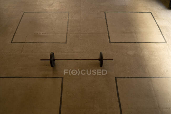 De cima de barra de metal pesado colocado no chão em instalações espaçosas de ginásio moderno — Fotografia de Stock